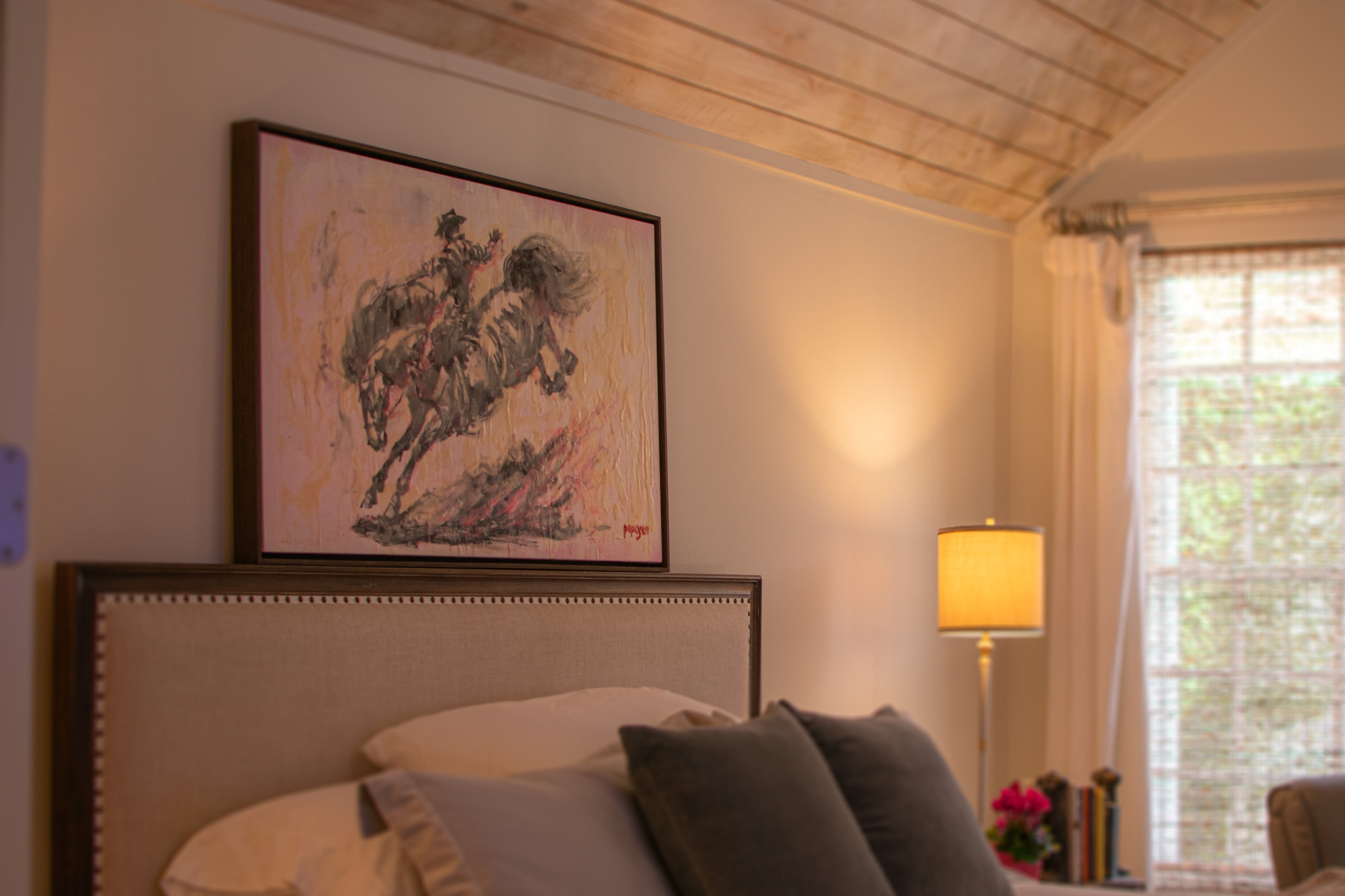 Bedroom with a painting of a horse on the wall, lamp, and window.